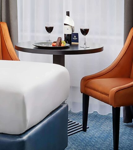 Cosy hotel room with a couple enjoying wine and cheese by the window.