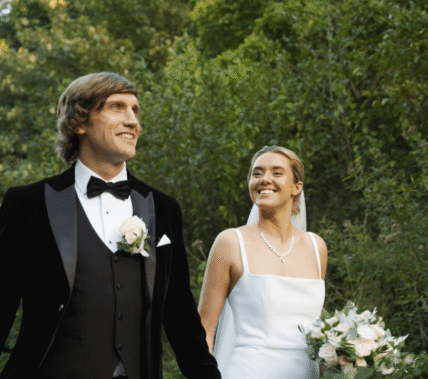 A couple joyfully strolls through lush gardens at Springfield Hotel on a sunny day.