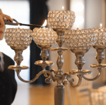 Elegant hotel dining setting with ornate candelabra being lit by staff.