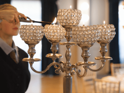 Elegant hotel dining setting with ornate candelabra being lit by staff.