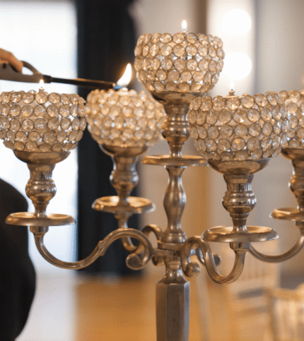 Elegant hotel dining setting with ornate candelabra being lit by staff.