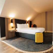 Cosy hotel room with a double bed and yellow suitcase.