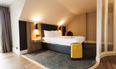 Cosy hotel room with a double bed and yellow suitcase.