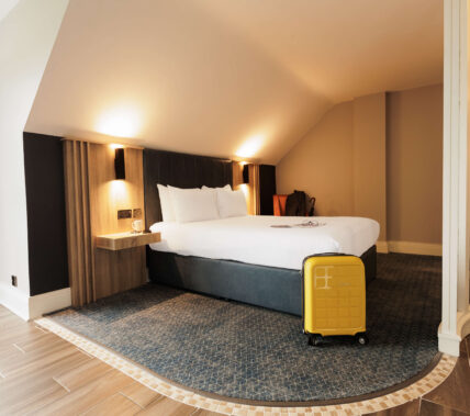 Cosy hotel room with a double bed and yellow suitcase.