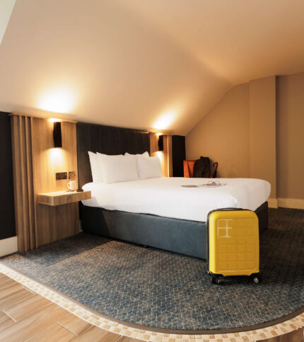 Cosy hotel room with a double bed and yellow suitcase.