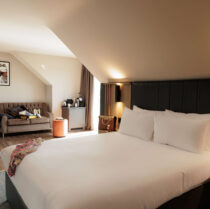 Cosy hotel room with king-sized bed and welcoming seating area for families or couples.