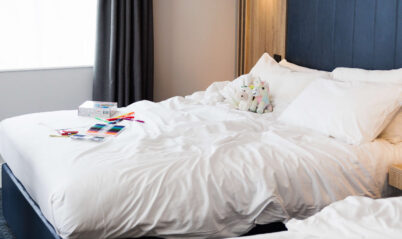 Inviting hotel room with cosy double beds, soft lighting, and a family's belongings.