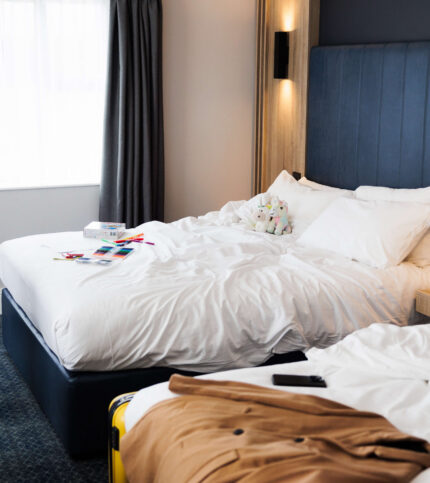 Inviting hotel room with cosy double beds, soft lighting, and a family's belongings.