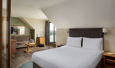 Inviting hotel room with a plush bed, seating area, and scenic window view.