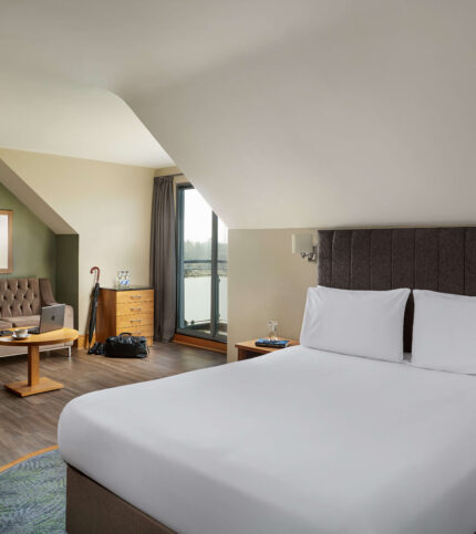 Inviting hotel room with a plush bed, seating area, and scenic window view.