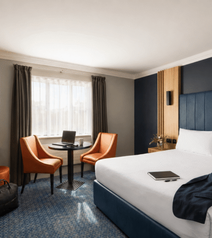 Modern hotel room with a cosy double bed, seating area, and working desk.