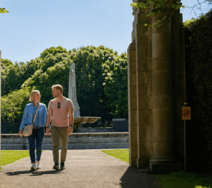 Couple strolling through Springfield Hotel garden with fountain and lush greenery.