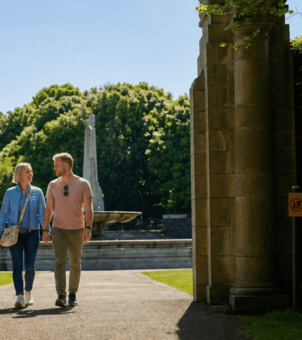 Couple strolling through Springfield Hotel garden with fountain and lush greenery.
