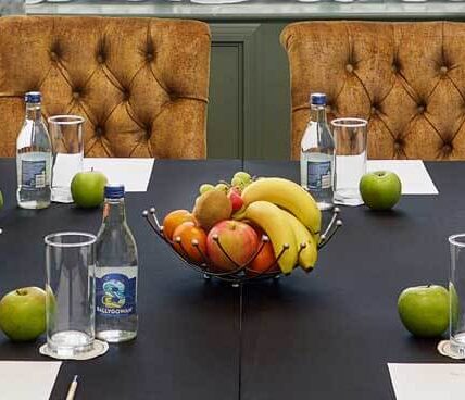 Hotel meeting room with fruit and water bottles on a conference table.