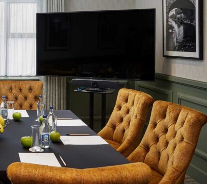 Elegant conference room with plush chairs and a large TV, set for a meeting at Springfield Hotel.