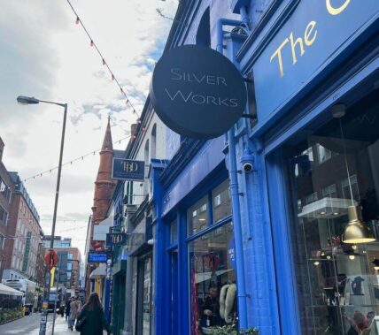 A person strolls past charming blue shopfronts on a lively Springfield street.