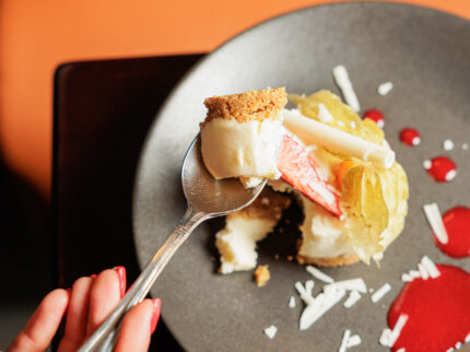 Elegant dessert with cheesecake and fruit garnish in a cosy hotel setting.