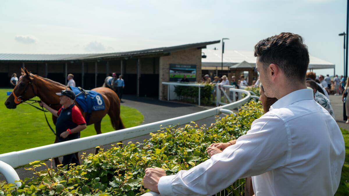 A couple watches a horse race at Springfield Hotel on a sunny day.