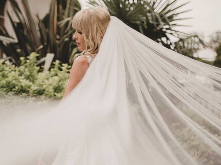 Bride with flowing veil in lush garden at Springfield Hotel.