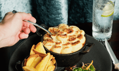A close-up of a hand serving a warm bread dish with chips and salad at Springfield Hotel.