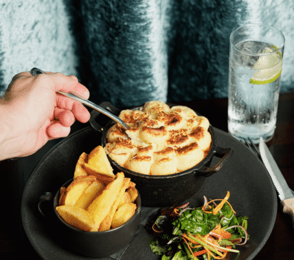 A close-up of a hand serving a warm bread dish with chips and salad at Springfield Hotel.