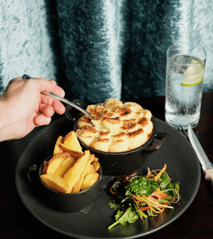 A close-up of a hand serving a warm bread dish with chips and salad at Springfield Hotel.