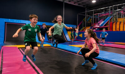 Children joyfully bouncing on trampolines in a vibrant indoor play area.