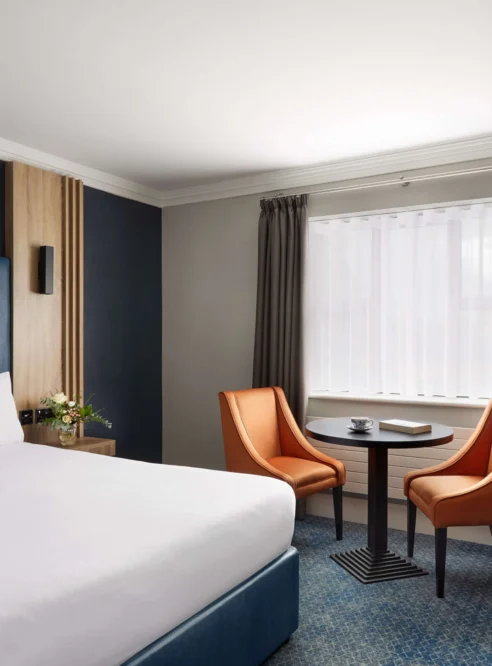 Bright family-friendly hotel room with king bed, seating for two, desk, and window light